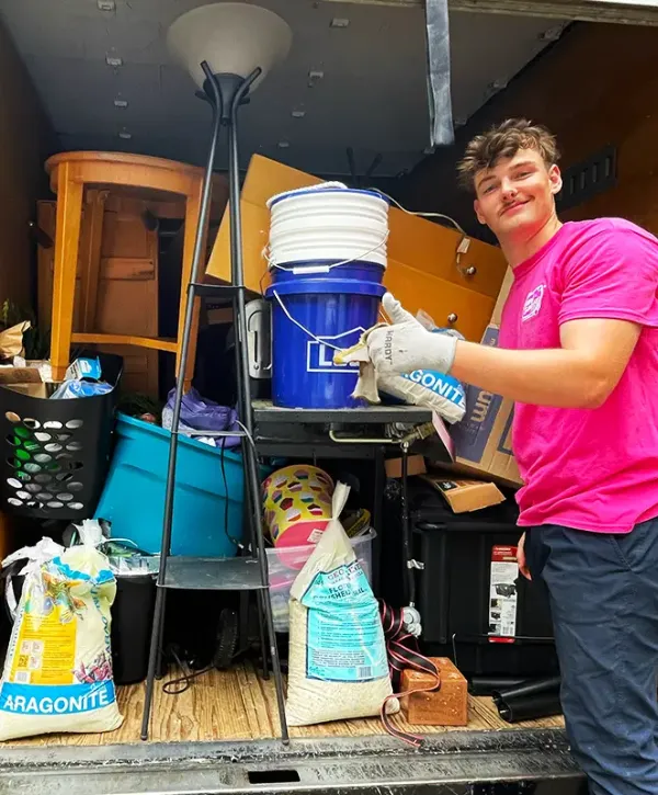 junk galaxy worker standing in front of truck ful of furniture and junk