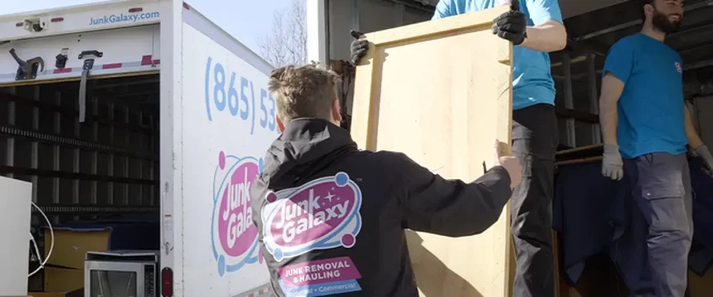 junk removal professional contractors expertly load large wooden furniture into white moving truck