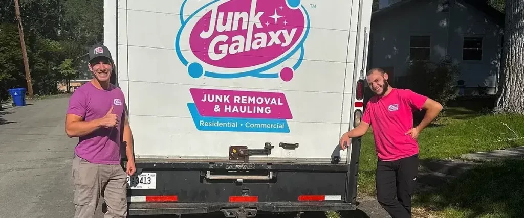 Two Junk Galaxy team members standing beside company junk removal truck.