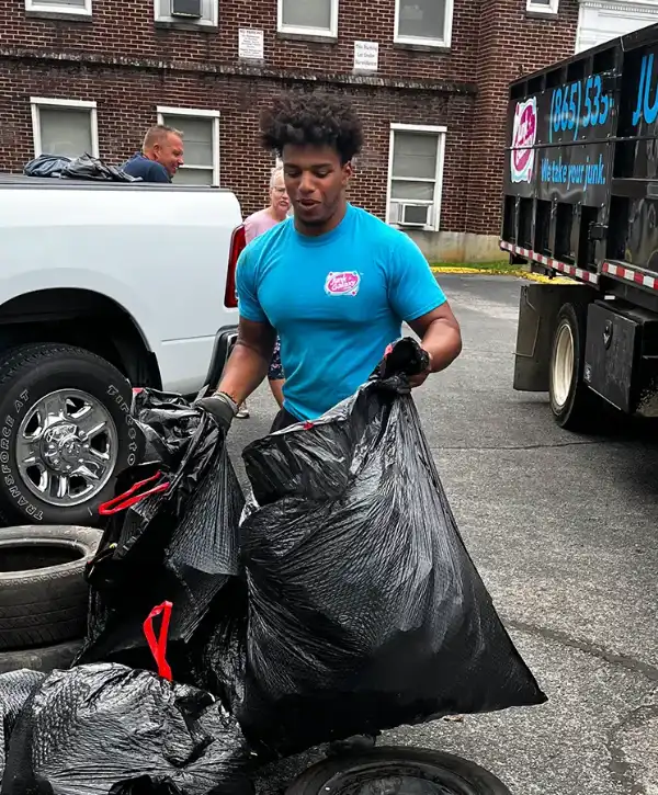 a Junk Galaxy worker carrying large bags full of unwanted items during a hoarder cleanout project