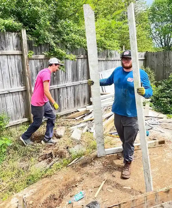 two Junk Galaxy workers in a yard with debris scattered around during a demolition project
