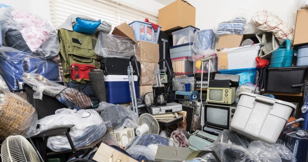 A massive pile of stacked storage bins, old electronics, and household goods illustrating the scale of hoarder cleanouts vs regular cleanouts.