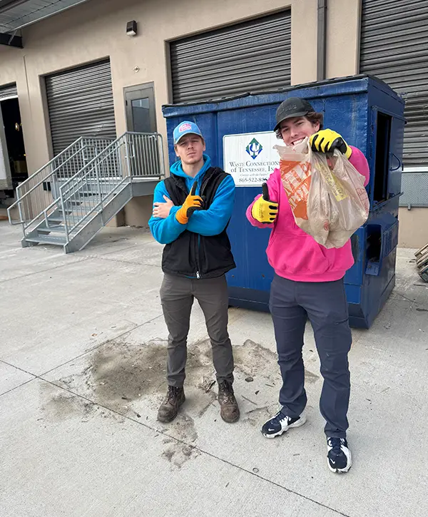 Junk removal crew cleaning commercial debris and loading waste into Junk Galaxy dumpster truck