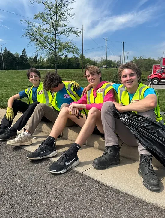 Junk removal team wearing safety vests during an outdoor cleanup and hauling job
