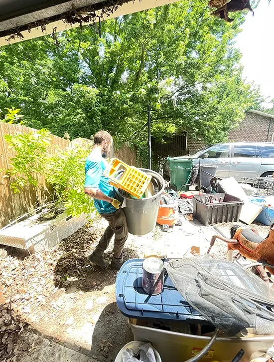 Junk removal worker clearing household clutter and unwanted items from a residential property